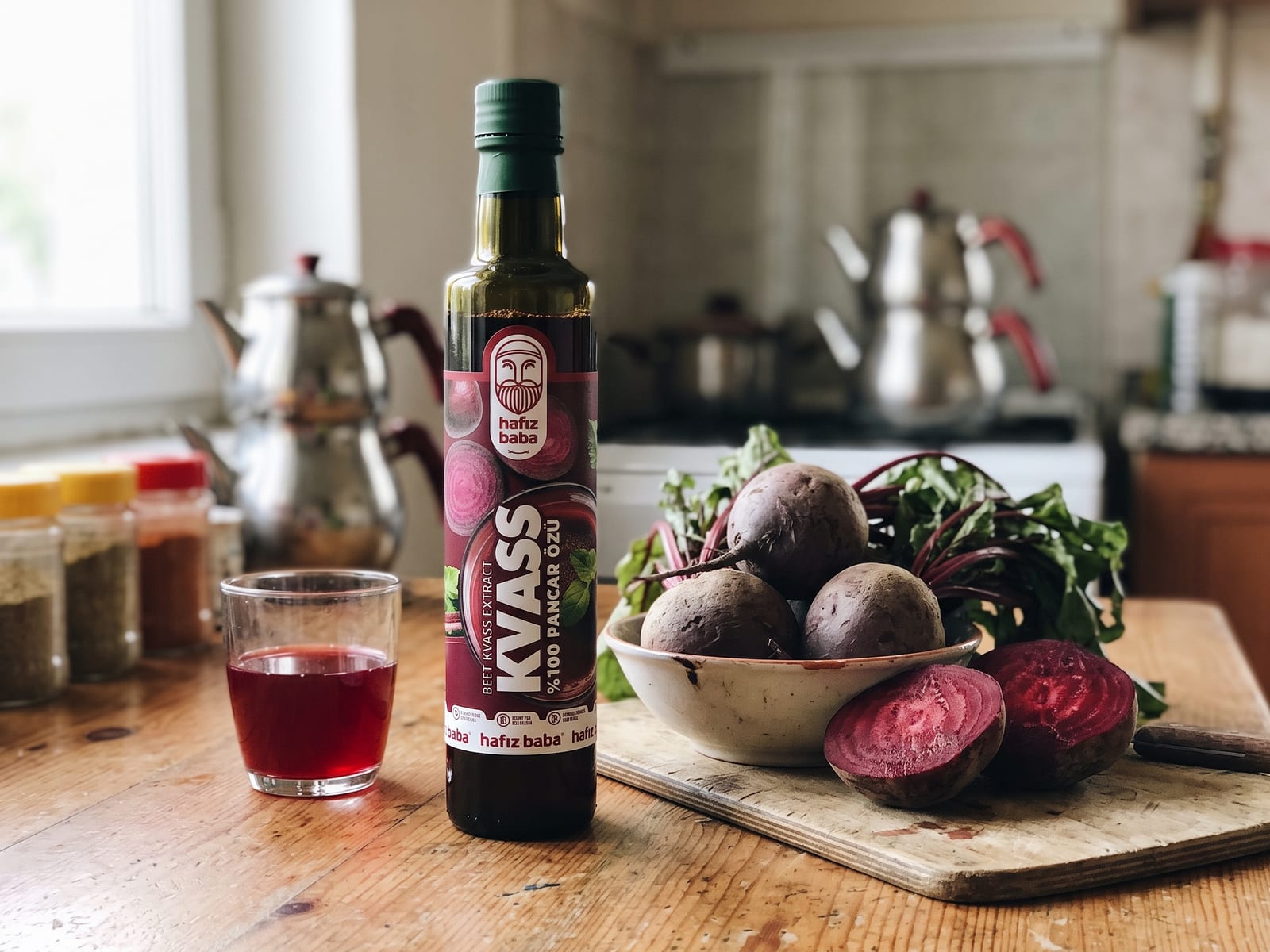 Ahşap masada Hafızbaba Kvass şişesi, cam bardakta pancar içeceği ve yanında taze kesilmiş kırmızı pancarlar.